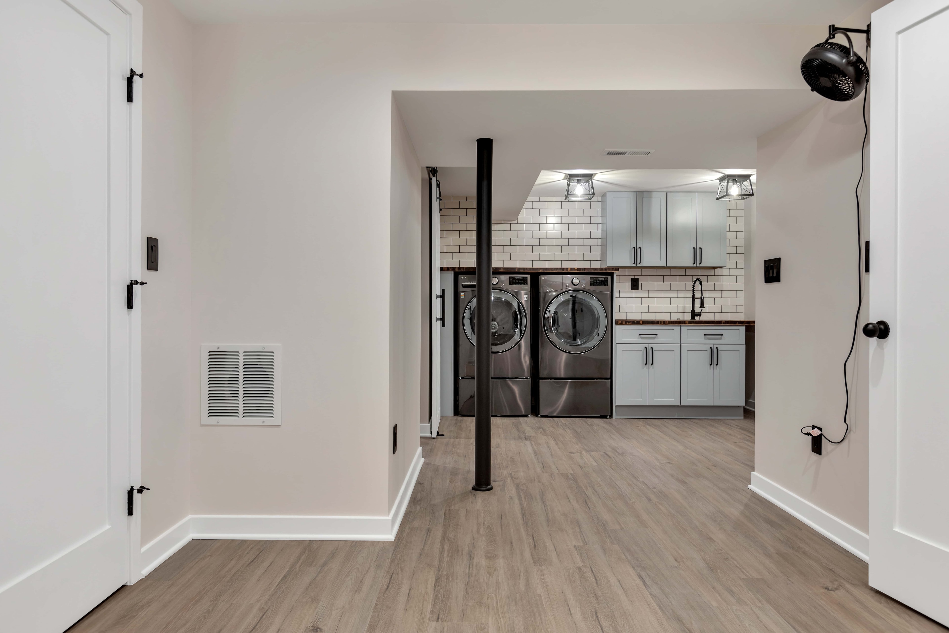Laundry room hallway view Maryland — gray shaker cabinetry, LG washer dryer, subway tile, sustainable home renovation