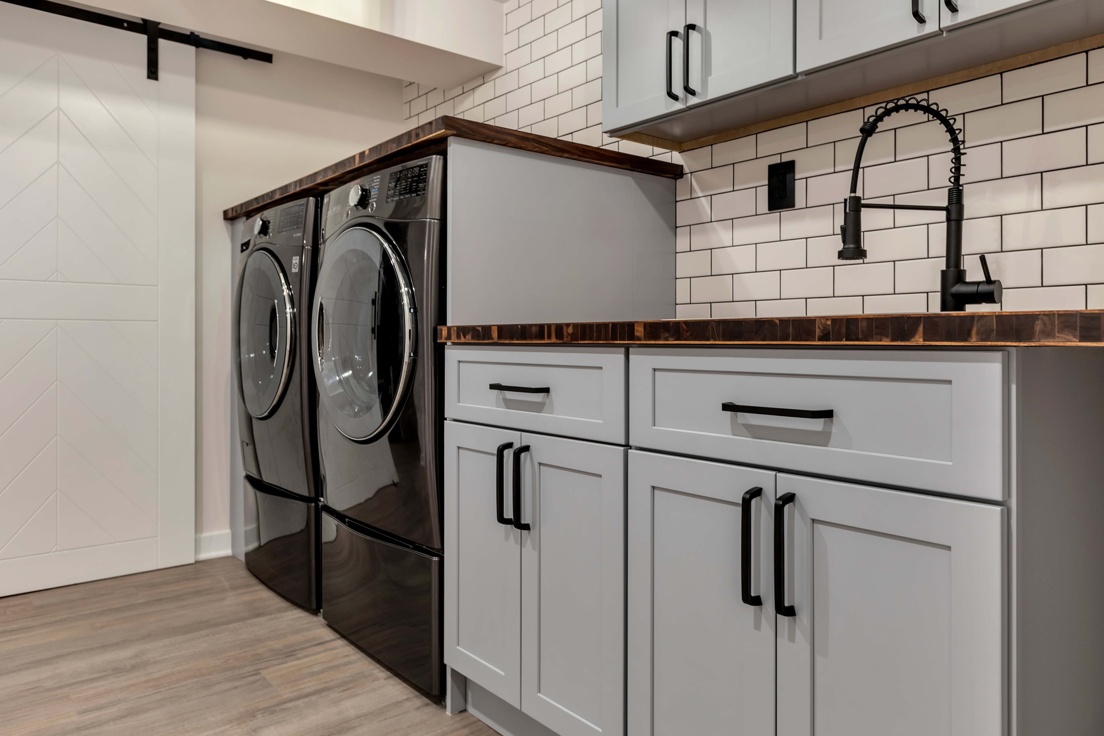 Laundry room barn door renovation Maryland — LG washer dryer, gray shaker cabinets, subway tile, zero-VOC paint finish