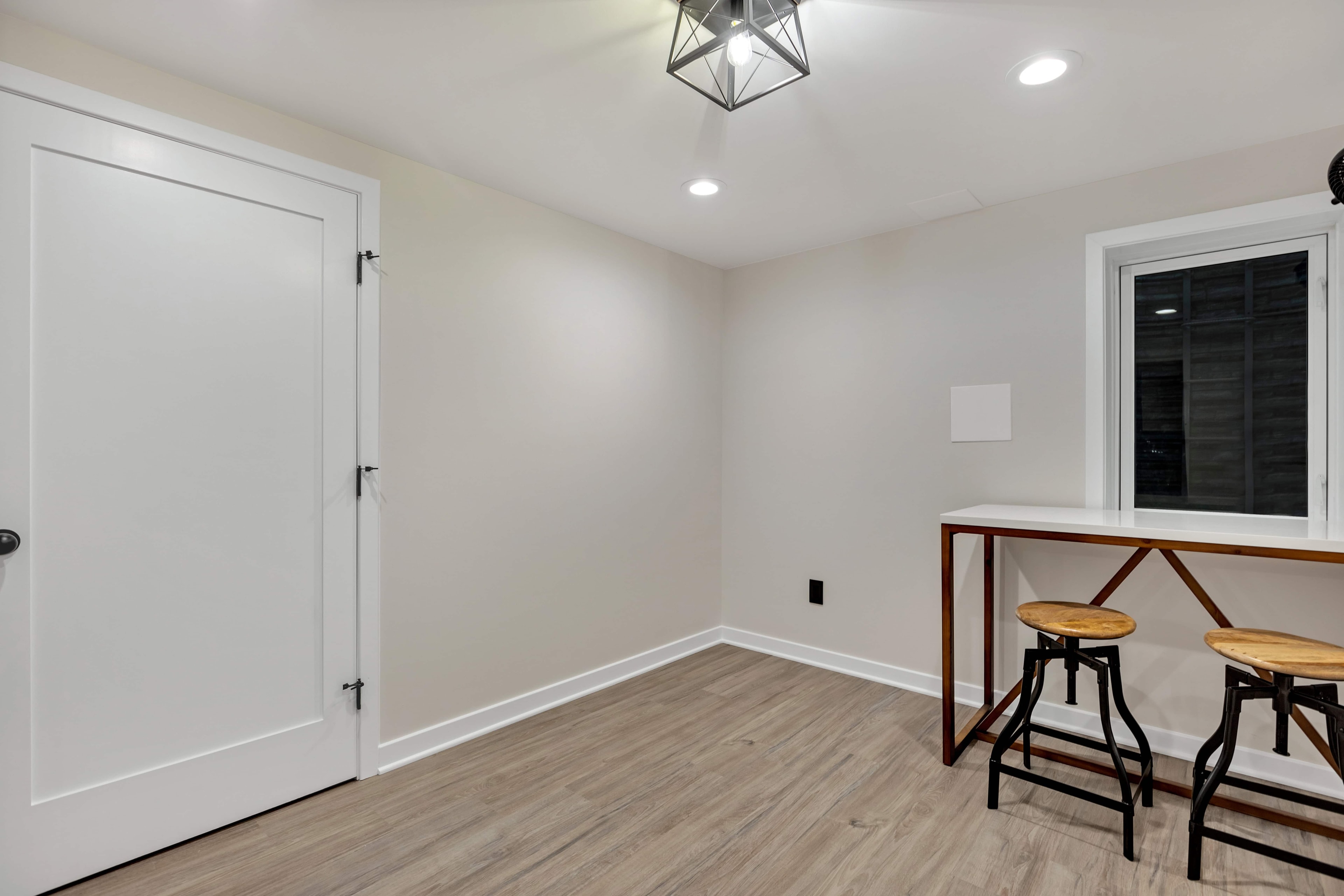 Finished basement room at night Maryland — geometric pendant light, LVP flooring, white trim, eco-friendly basement renovation by Alleco Center