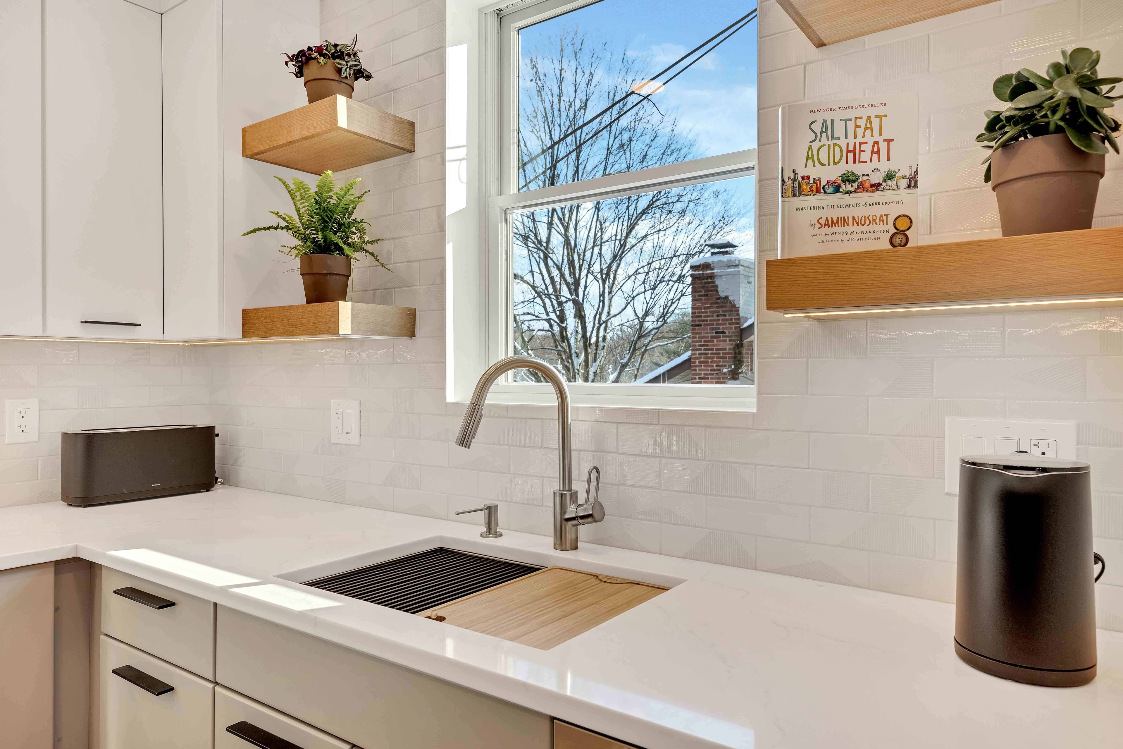 Kitchen peninsula renovation Maryland — floating wood shelves, subway tile, undermount sink, open living area, eco-friendly design-build